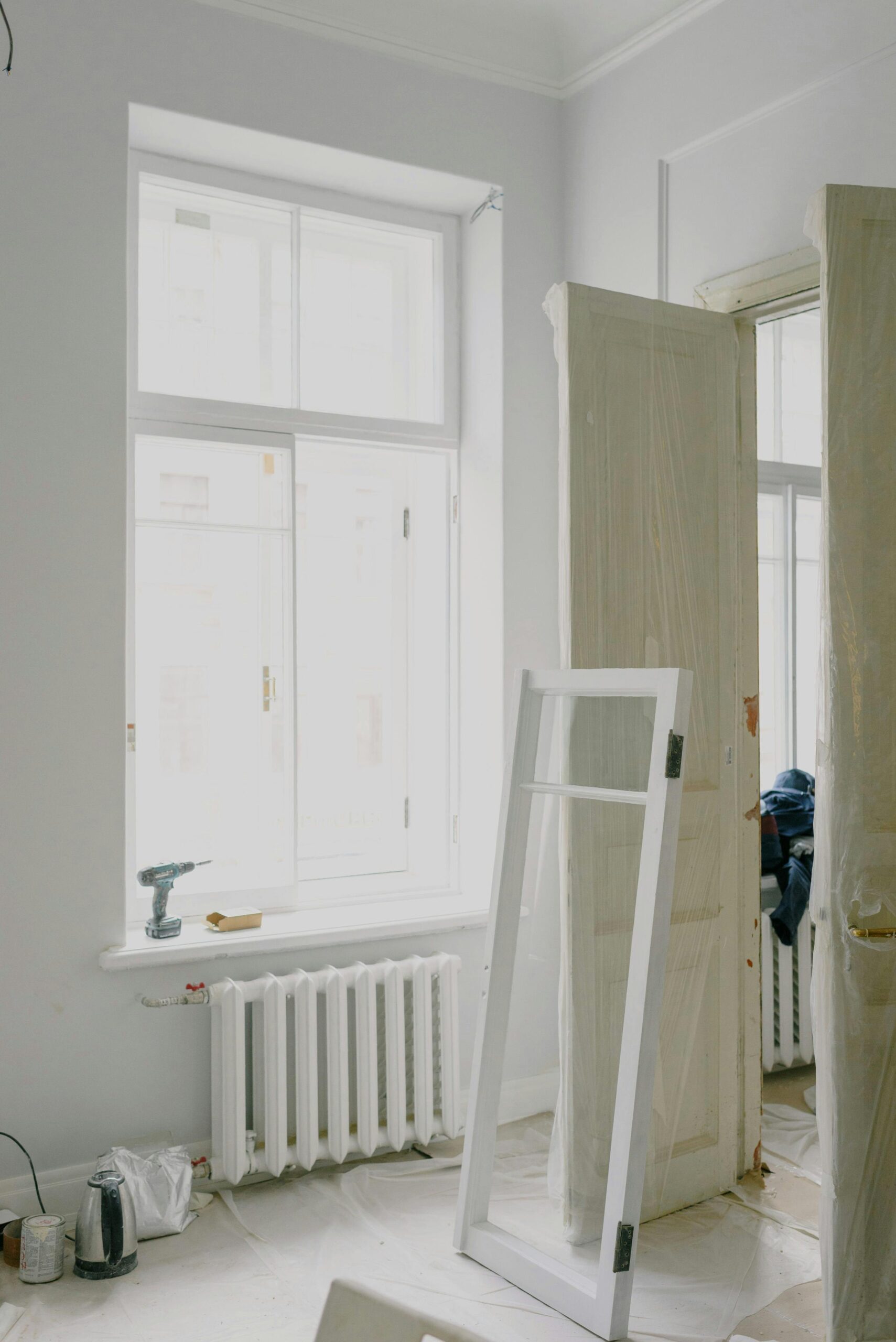 Bright room under renovation featuring white walls and windows, showcasing minimalist design.